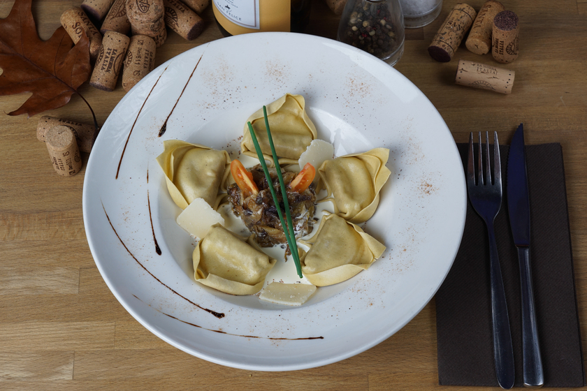 A crown of ravioli cheerfully drizzled with chicory and cream sauce