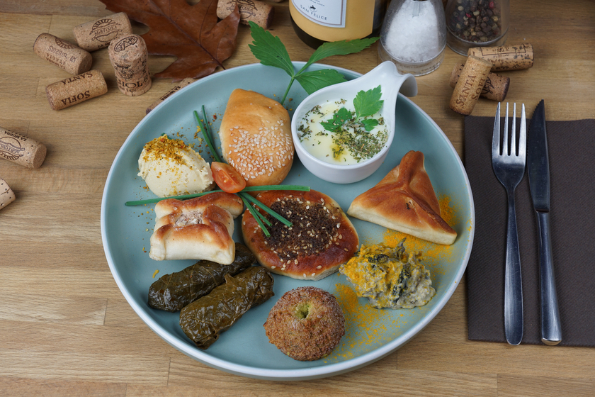 A tasty plate containing a spinach turnover, a cheese and thyme puff pastry, a meat turnover, hummus and moutabal